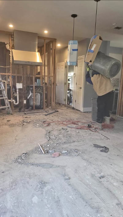 Kitchen gutted to the studs while a crew member carries out debris and cabinetry
