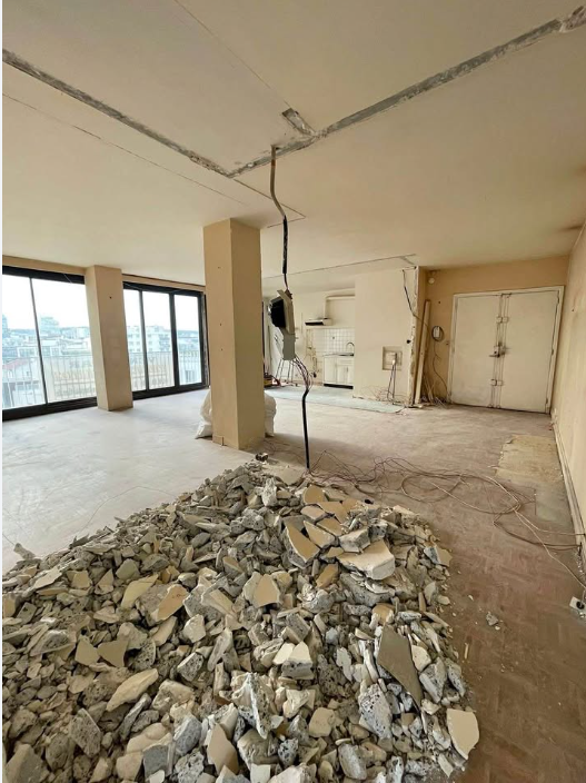 Condo interior stripped bare with a pile of broken concrete slab rubble on the floor