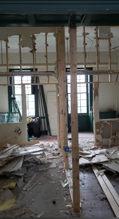 Partition walls stripped back to bare studs with drywall debris covering the floor