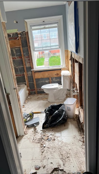 Bathroom demolition with tub, tile and walls removed down to block and studs