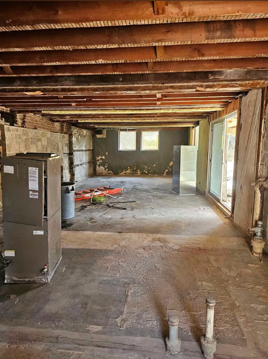 Basement stripped back to original floor joists, block walls and concrete floor after a full gut-out