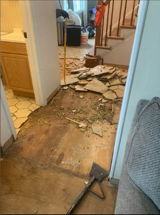 Tile and hardwood flooring pried up to the subfloor with debris and tools on site