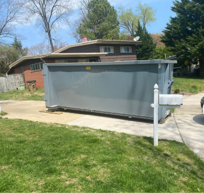 Roll-off disposal bin placed on a residential driveway for demolition debris removal