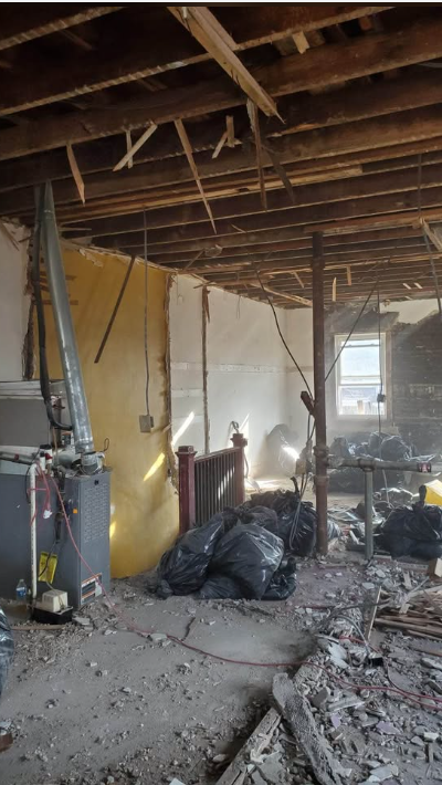 Interior of a home stripped to joists and studs with debris bagged for removal during a demolition job