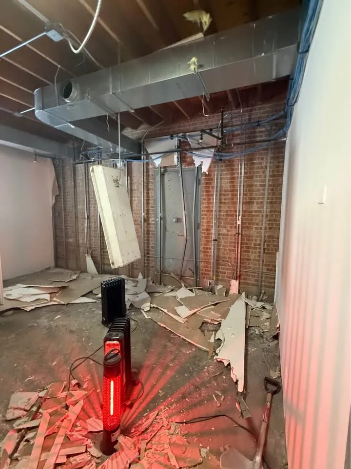 Office room opened to brick and ductwork with drywall across the floor
