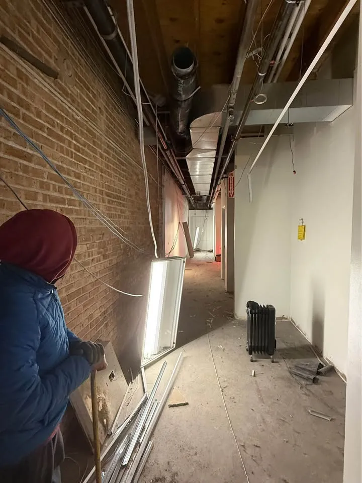 Crew member in a commercial hallway as ceiling fixtures and conduit come down