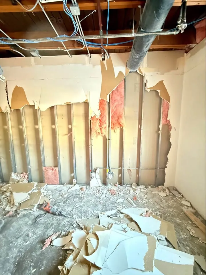 Drywall torn from metal studs with insulation exposed in a commercial unit