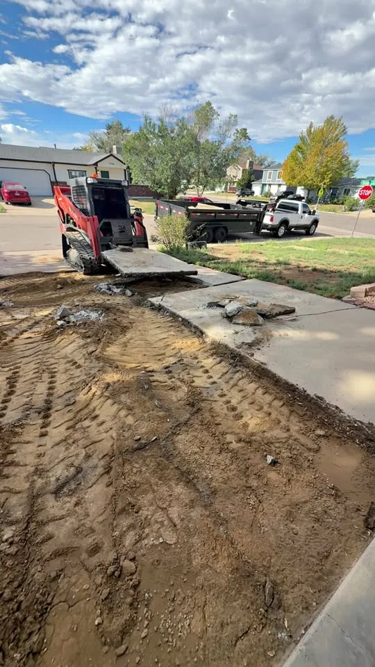 Compact track loader removing an old driveway with the gravel base exposed