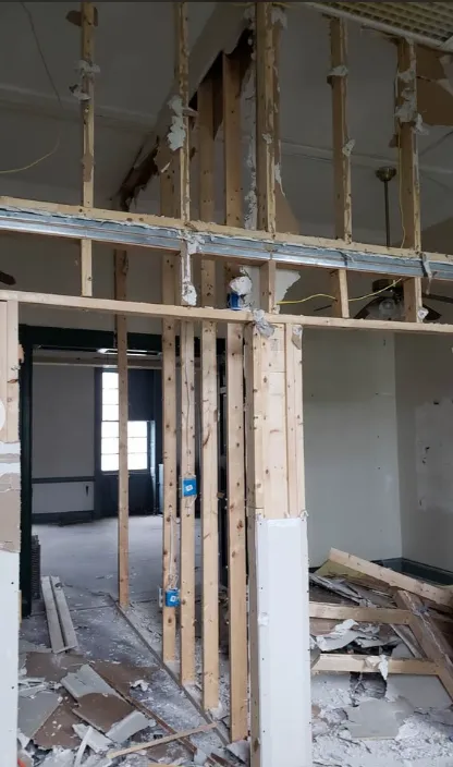 Interior wall taken back to studs and blue electrical boxes ahead of a layout change
