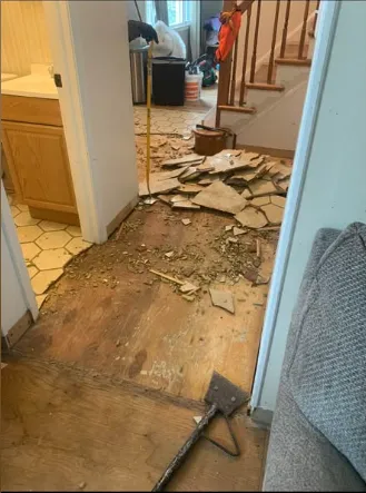 Hallway flooring torn up to the subfloor at the foot of a staircase