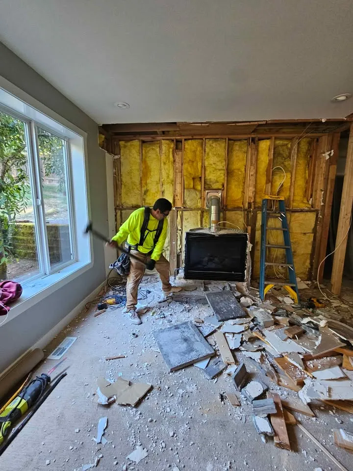 Worker in a high-visibility shirt breaking out a fireplace surround