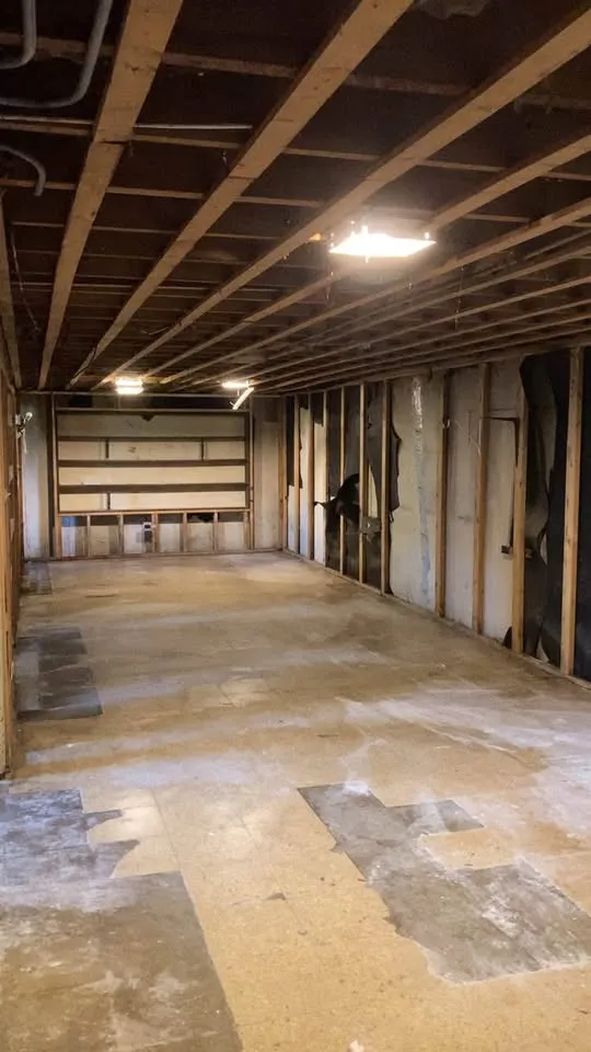 Long basement room gutted to joists and studs with the floor cleared