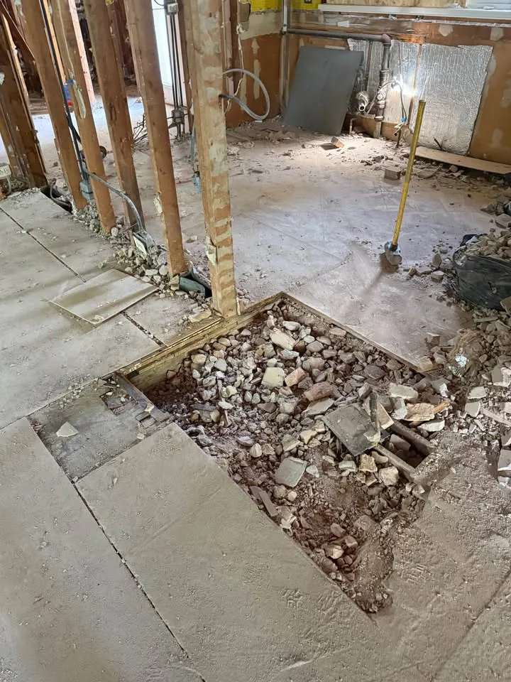 Section of subfloor cut out and filled with debris between wall studs