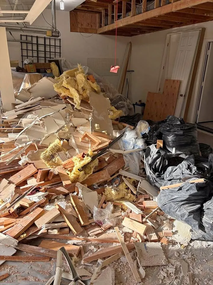 Pile of lumber, insulation and drywall collected in the middle of a gutted room