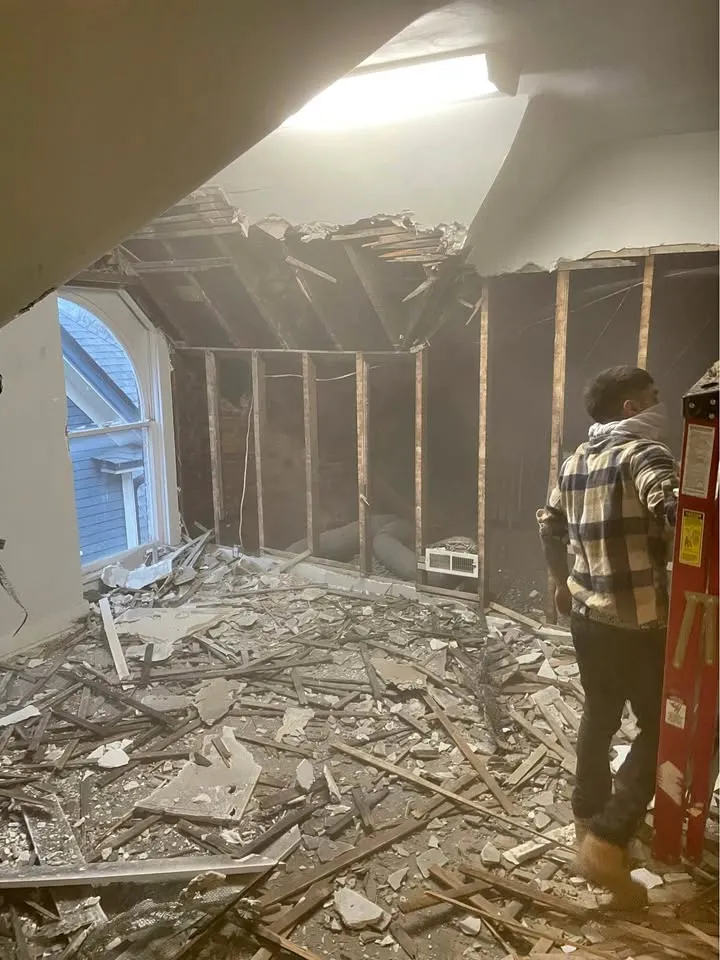 Crew member standing in an attic room where the ceiling and walls have been pulled down