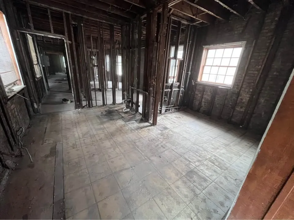 Older house interior gutted to studs with the original plank floor exposed