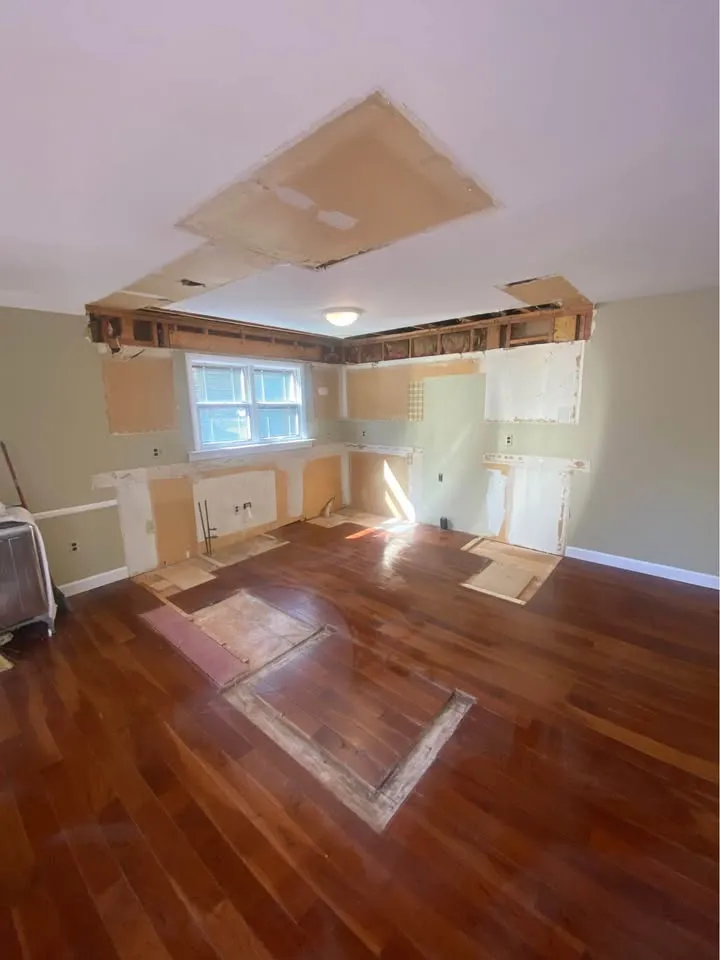 Kitchen cleared of cabinets with cut-outs in the hardwood and bulkhead removed
