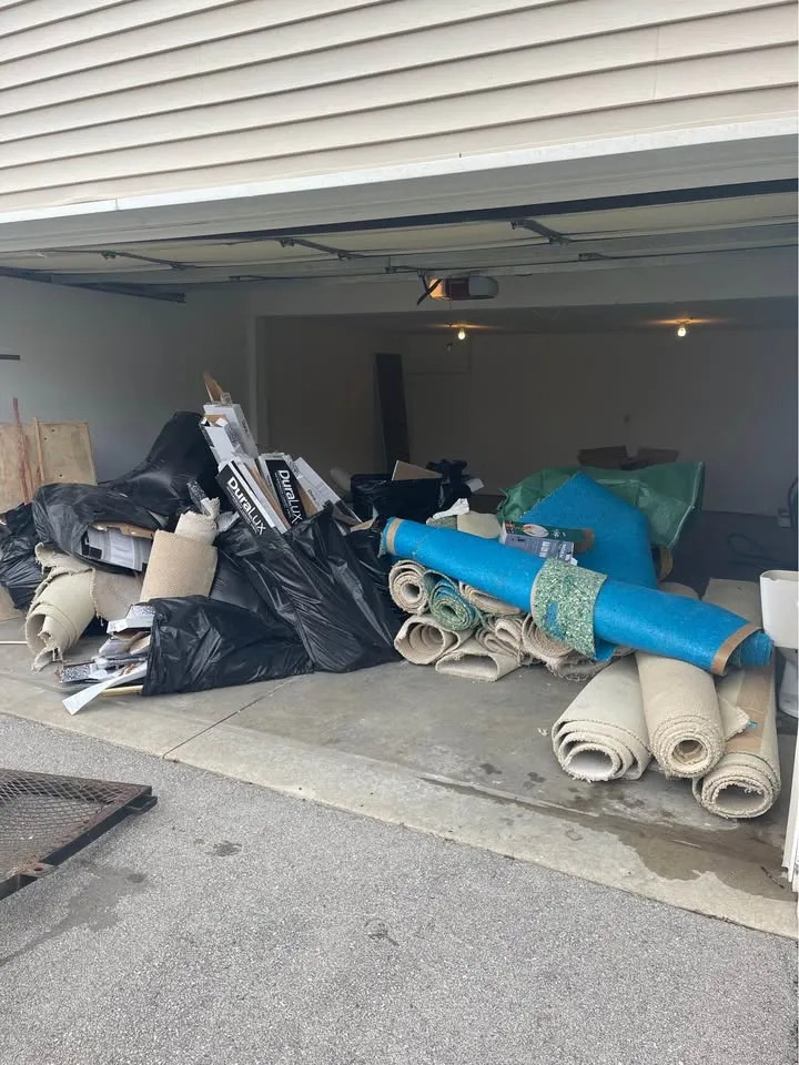 Garage full of rolled carpet, bags and materials ready to be hauled away