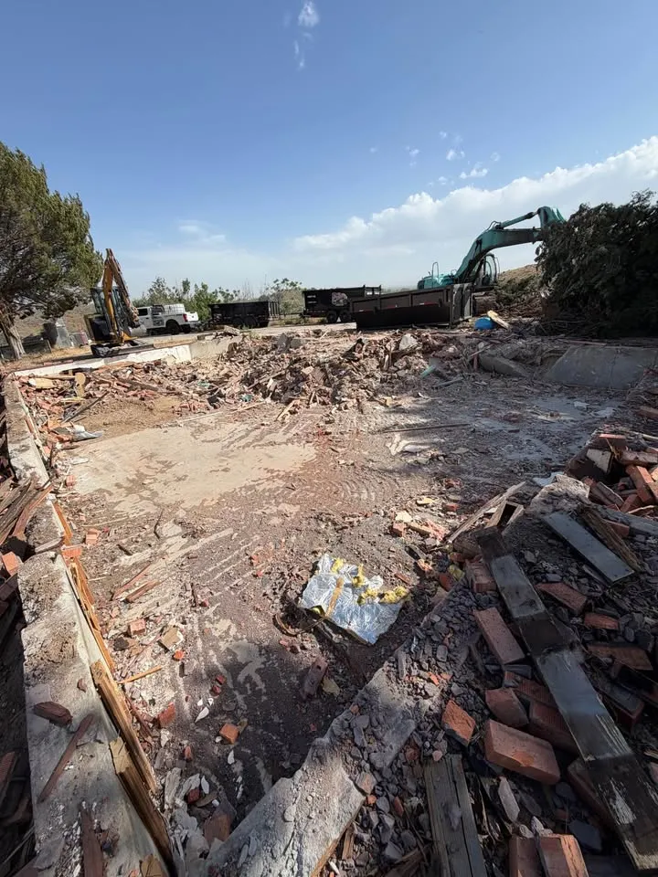 Excavator working through the rubble of a house taken down to its foundation