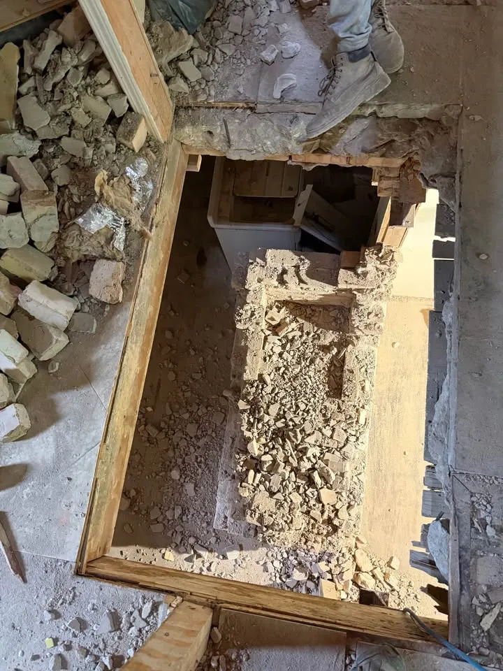 View down through a floor opening onto chimney rubble on the level below