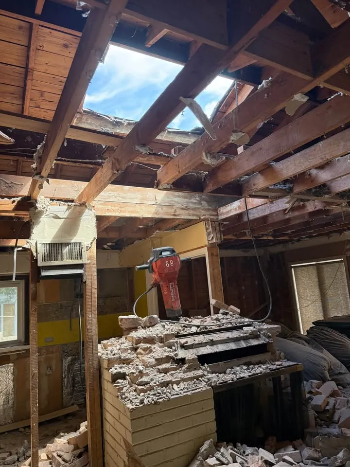 Jackhammer resting on a brick chimney being taken down under open roof joists
